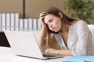 A frustrated white woman stares at her laptop screen